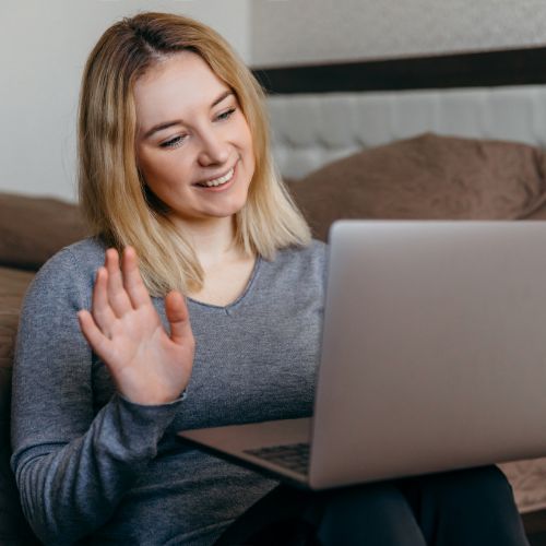 Woman on waiving toward a laptop screen to represent the Visibly Fit™ with Wendie Pett, ND video coaching call.